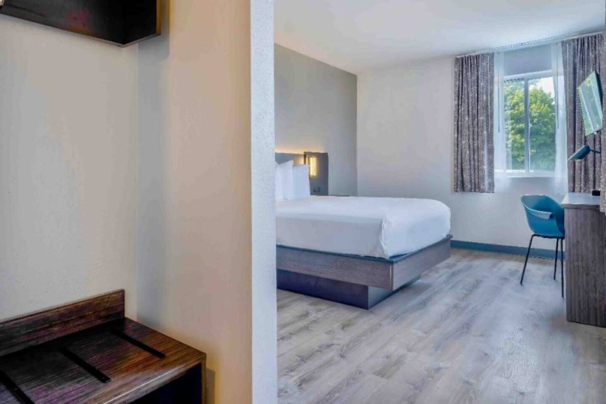 Habitación de hotel con cama, escritorio, silla y ventana.