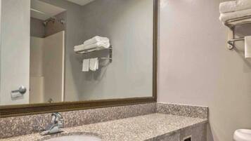 A bathroom with a granite countertop sink, a mirror, and a towel rack.