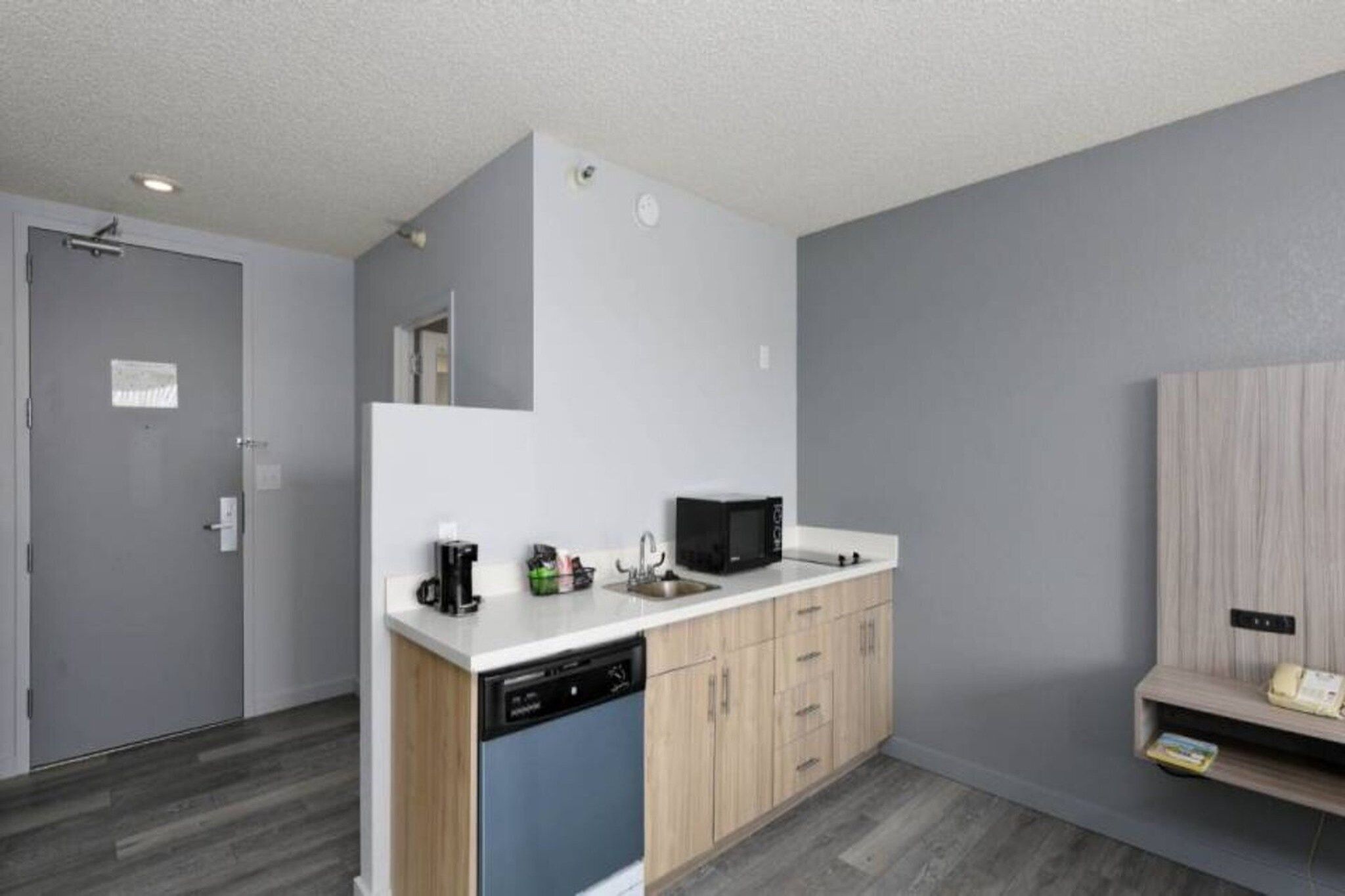 A compact kitchen with a dishwasher, a microwave, and a sink.