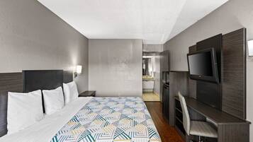 A hotel room with a bed, a TV, a desk, and a mirror.