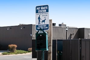 Un panneau indiquant un espace dédié à la collecte des excréments d’animaux de compagnie, avec une poubelle et le logo de Fido House.