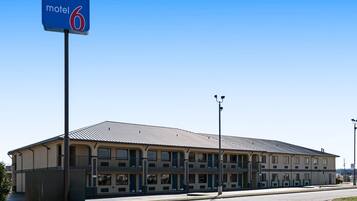 Un motel con un edificio grande de una sola planta, múltiples ventanas y un letrero llamativo que indica que es el motel número 6.