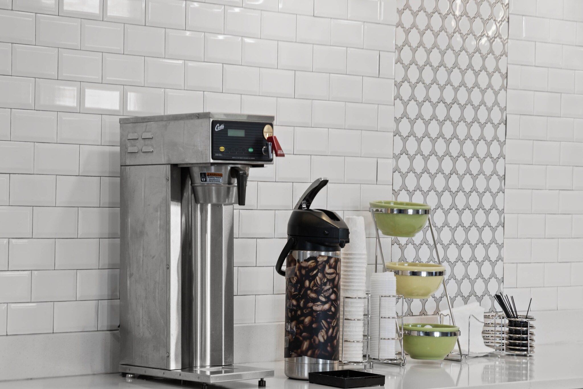 Een koffieapparaat met digitaal scherm, een koffiemolen en een set koffiekopjes en schotels.