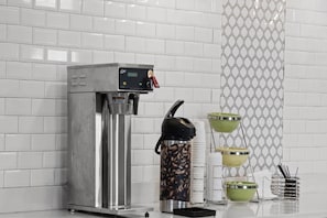 Une machine à café dotée d’un écran numérique, d’un moulin à café et d’un ensemble de tasses et de soucoupes.
