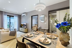Un salon moderne comprenant un coin repas, un canapé, un téléviseur et un grand miroir.
