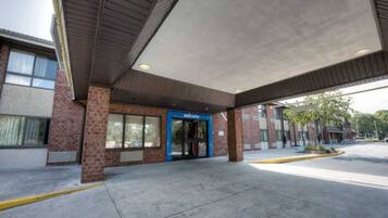 A building with a blue entrance marked 'welcome,' a covered parking area, and a brick facade.