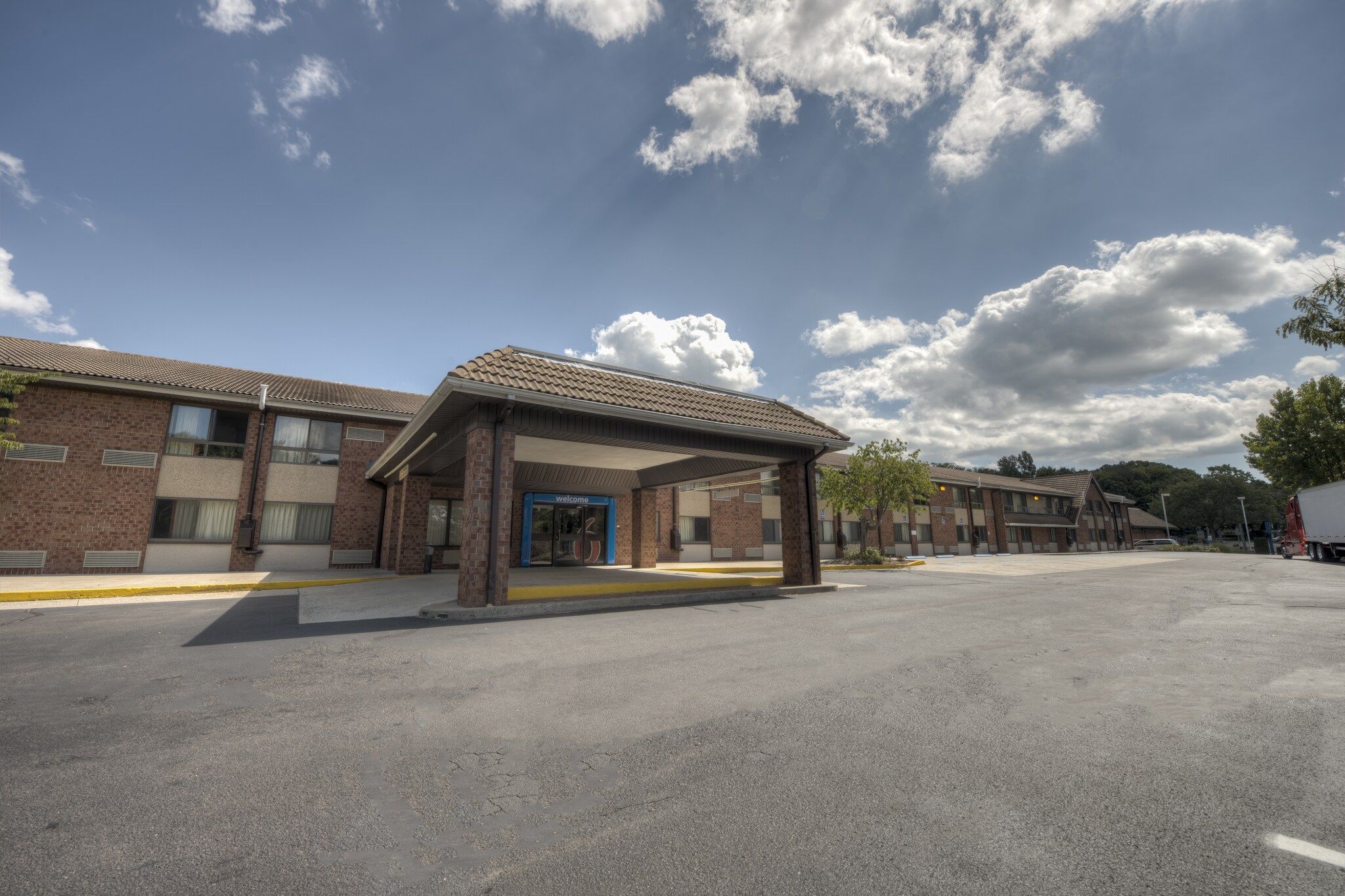 A motel with a covered entrance, multiple rooms, and a parking lot.