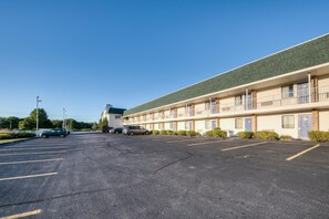 Ein Motel mit Parkplatz, mehreren Zimmern und einem grünen Dach.