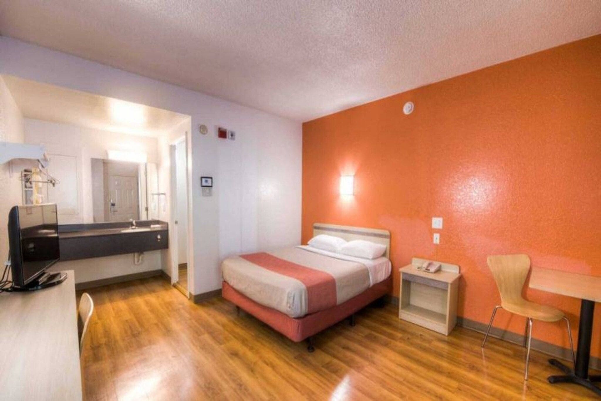 Een hotelkamer met een bed, nachtkastje, stoel en bureau met een computer.