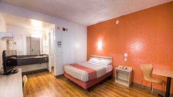 Een hotelkamer met een bed, nachtkastje, stoel en bureau met een computer.