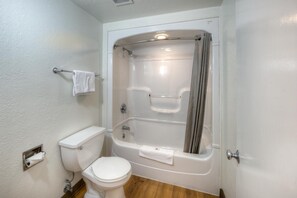 A bathroom with a toilet, a bathtub, and a shower curtain. - Cozy 1 Queen Bed | Micfridge (East Lyme)