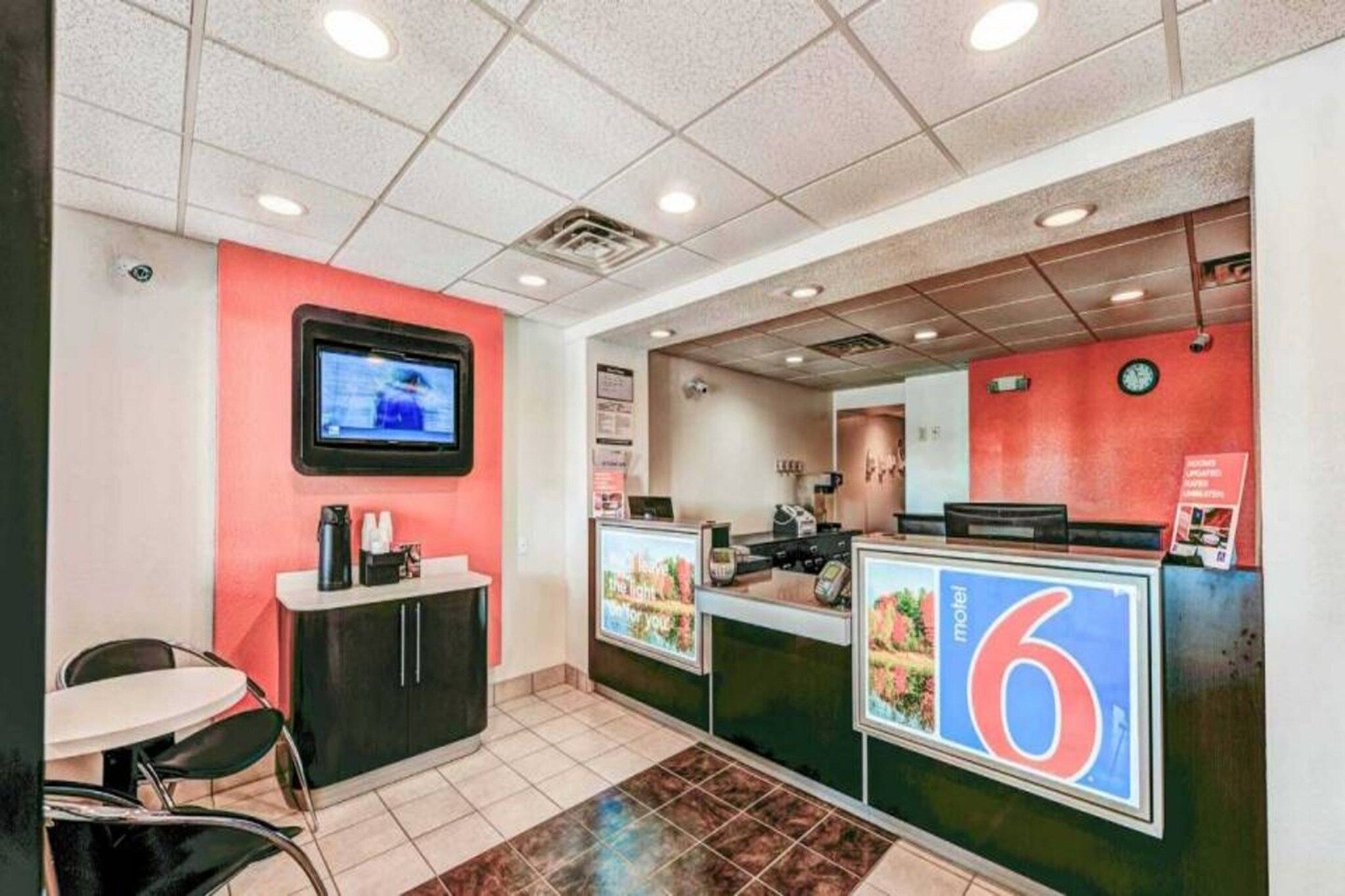 Interior de un restaurante con mostrador, zona de estar y una pantalla de televisión.