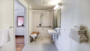 Un baño con ducha, un banco, un lavabo y un espejo.