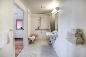 Un baño con ducha, un banco, un lavabo y un espejo.