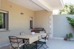 An outdoor patio with a table and chairs, a grill, and potted plants. - Villa Andrews by Wonderful Italy (Torre A Mare)