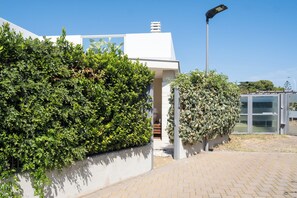 A modern building with a white facade, a large hedge, and a street lamp. - Villa Andrews by Wonderful Italy (Torre A Mare)