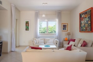 A living room with a sofa set, a coffee table, and a painting on the wall. - Villa Andrews by Wonderful Italy (Torre A Mare)