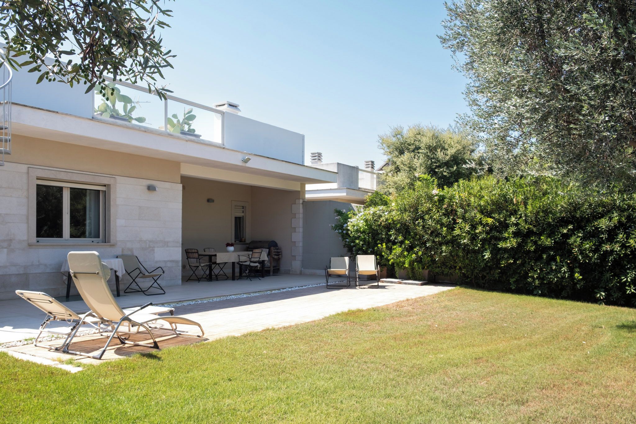Una casa moderna con un patio amoblado, que incluye mobiliario exterior y una mesa de comedor.
