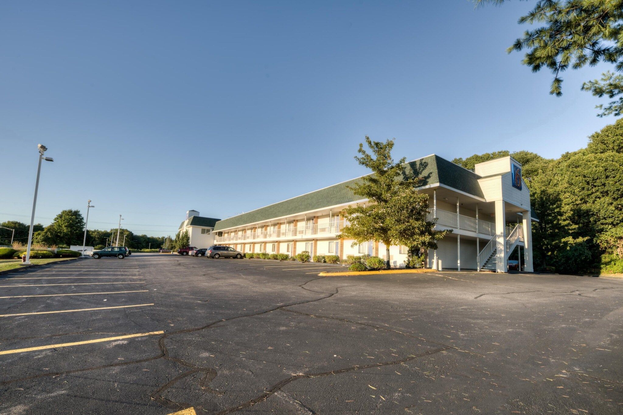 A multi-story motel with a parking lot in front.