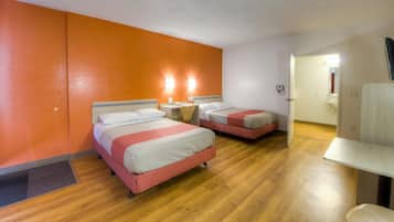 Habitación de hotel con dos camas, un escritorio, una silla y un baño visible a través de una puerta abierta.