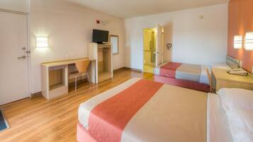 A hotel room with two beds, a desk, a chair, and a television.