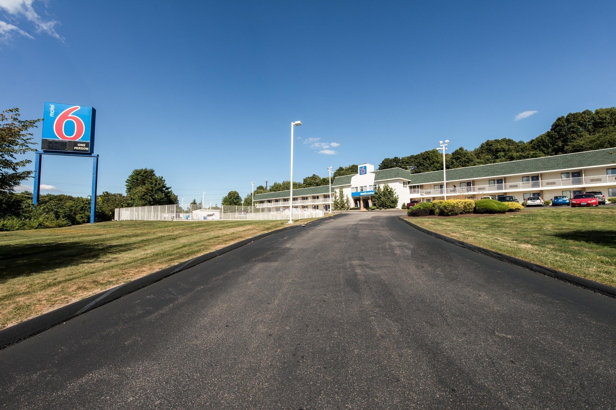 A motel with a clear road leading to the entrance, a fenced parking area, and a building with a '6' sign.