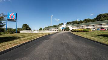 A motel with a clear road leading to the entrance, a fenced parking area, and a building with a '6' sign.