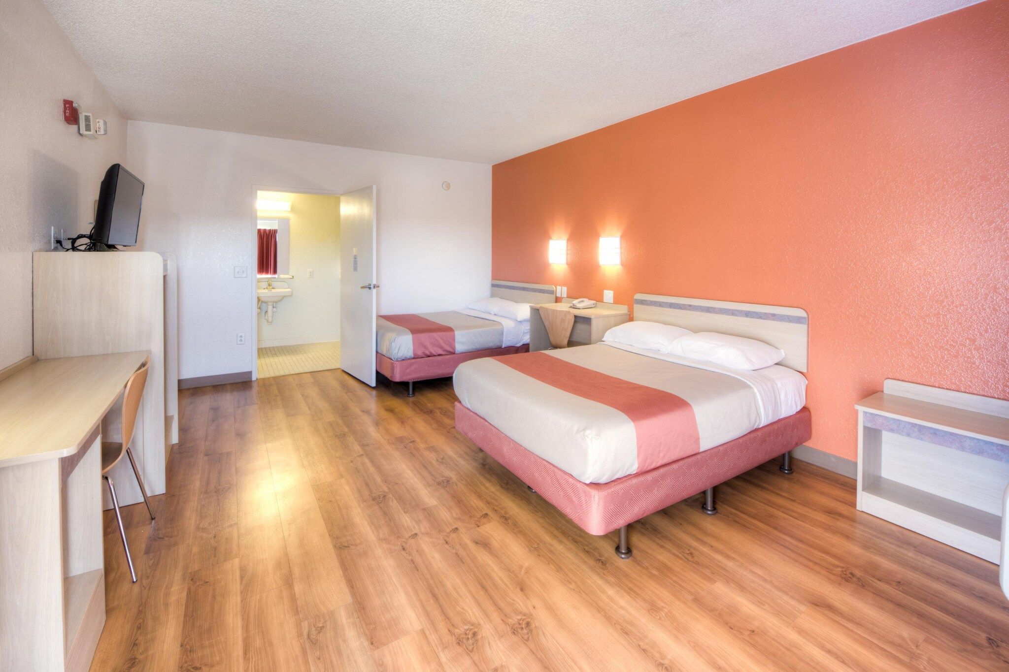 Habitación de hotel con dos camas, un escritorio y una silla.