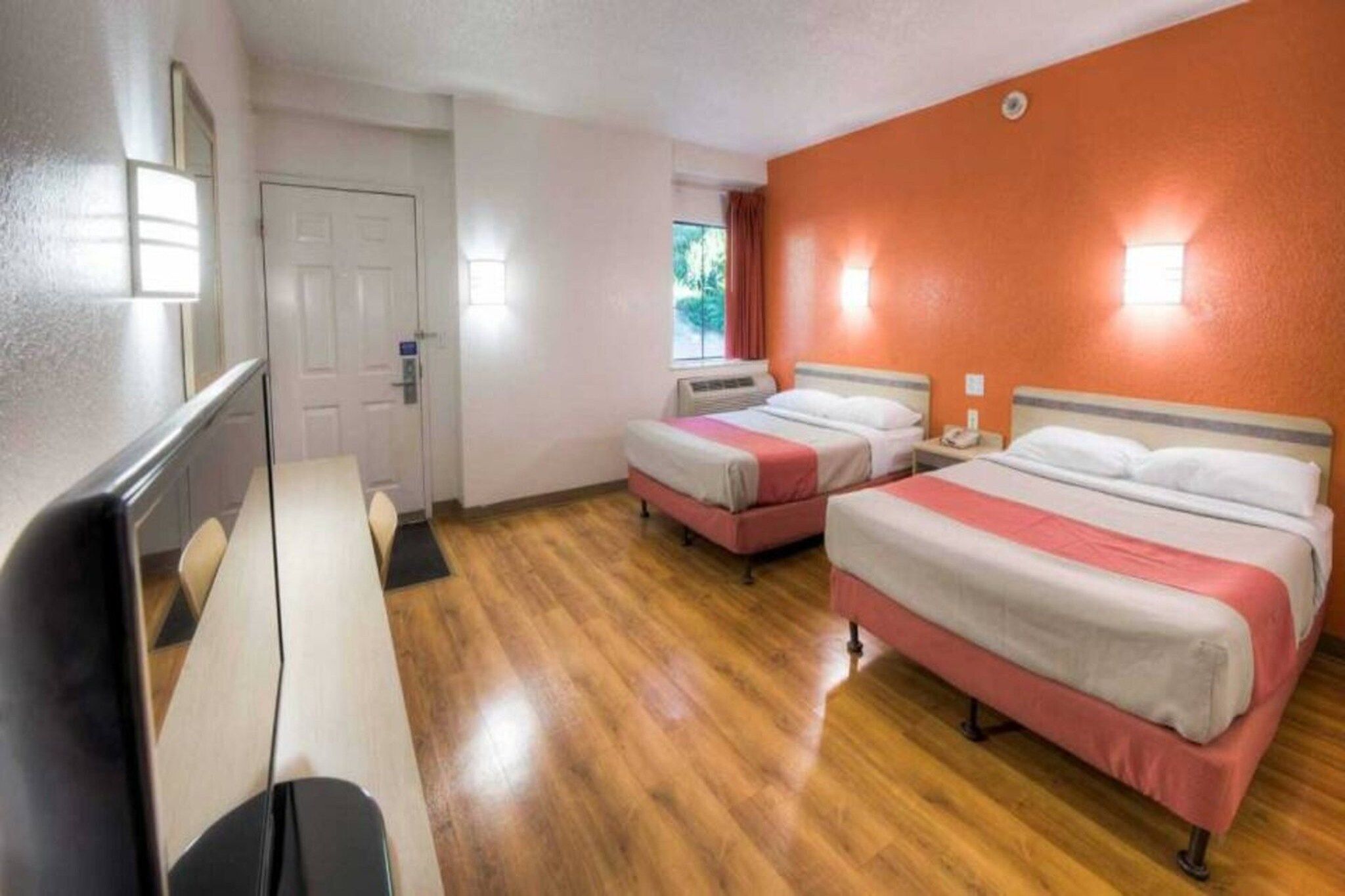 A hotel room with two beds, a desk, and a chair.