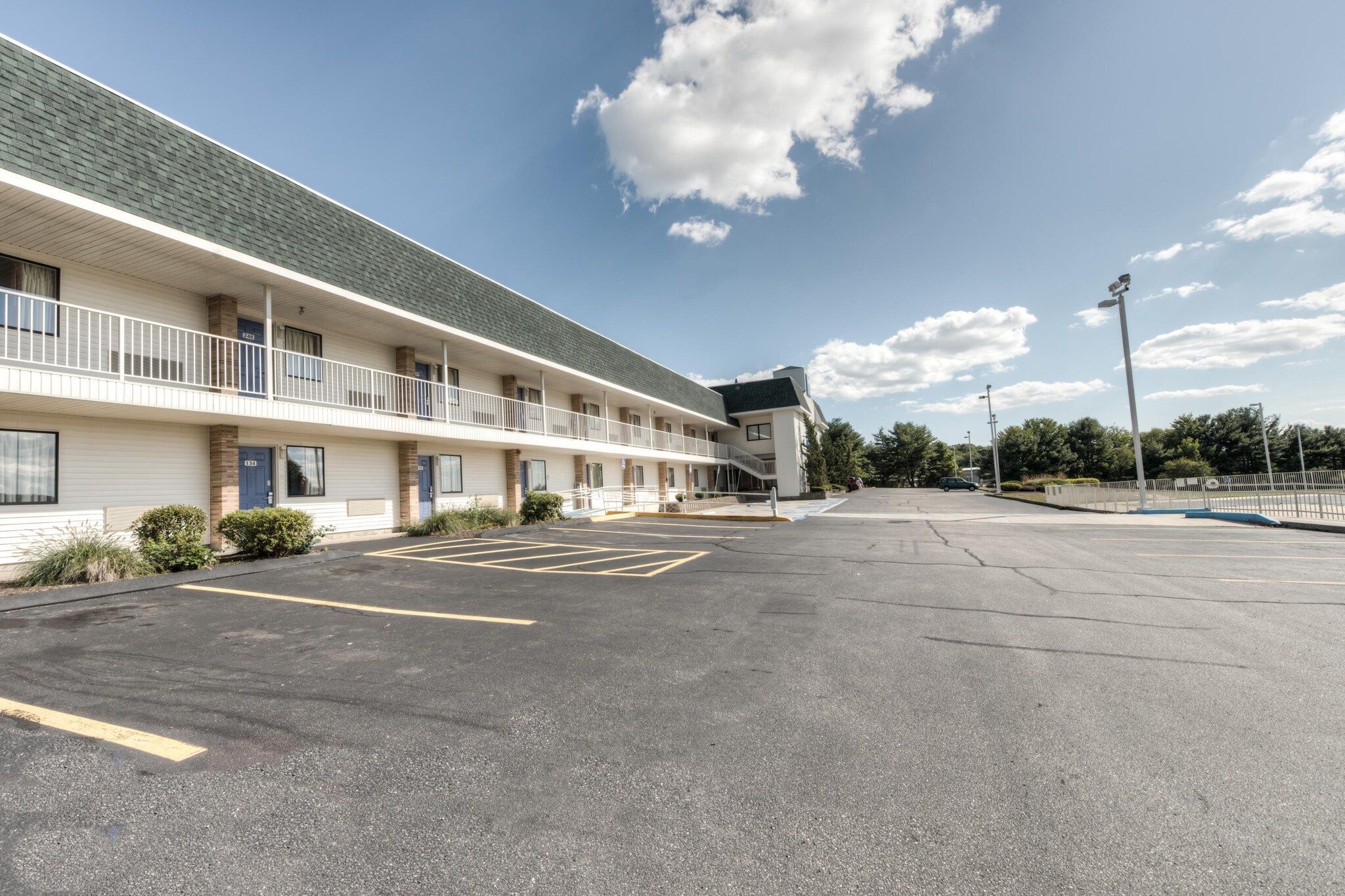 Un motel con estacionamiento, una galería techada y un edificio de techo plano.