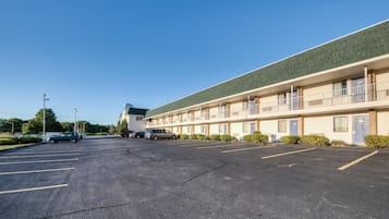 Un motel con estacionamiento, varias habitaciones y techo verde.