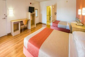 Ein Hotelzimmer mit zwei Betten, einem Schreibtisch und einem Fernseher.