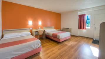 A hotel room with two beds, a desk, and a window with curtains.