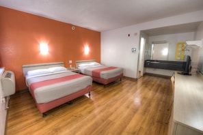 Habitación de hotel con dos camas, un escritorio con ordenador y un baño con espejo y lavabo.
