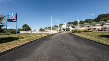 A motel with a clear road leading to the entrance, a fenced parking area, and a building with a '6' sign.