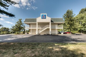 Un motel con una estructura de dos pisos, un acceso cubierto y un estacionamiento.
