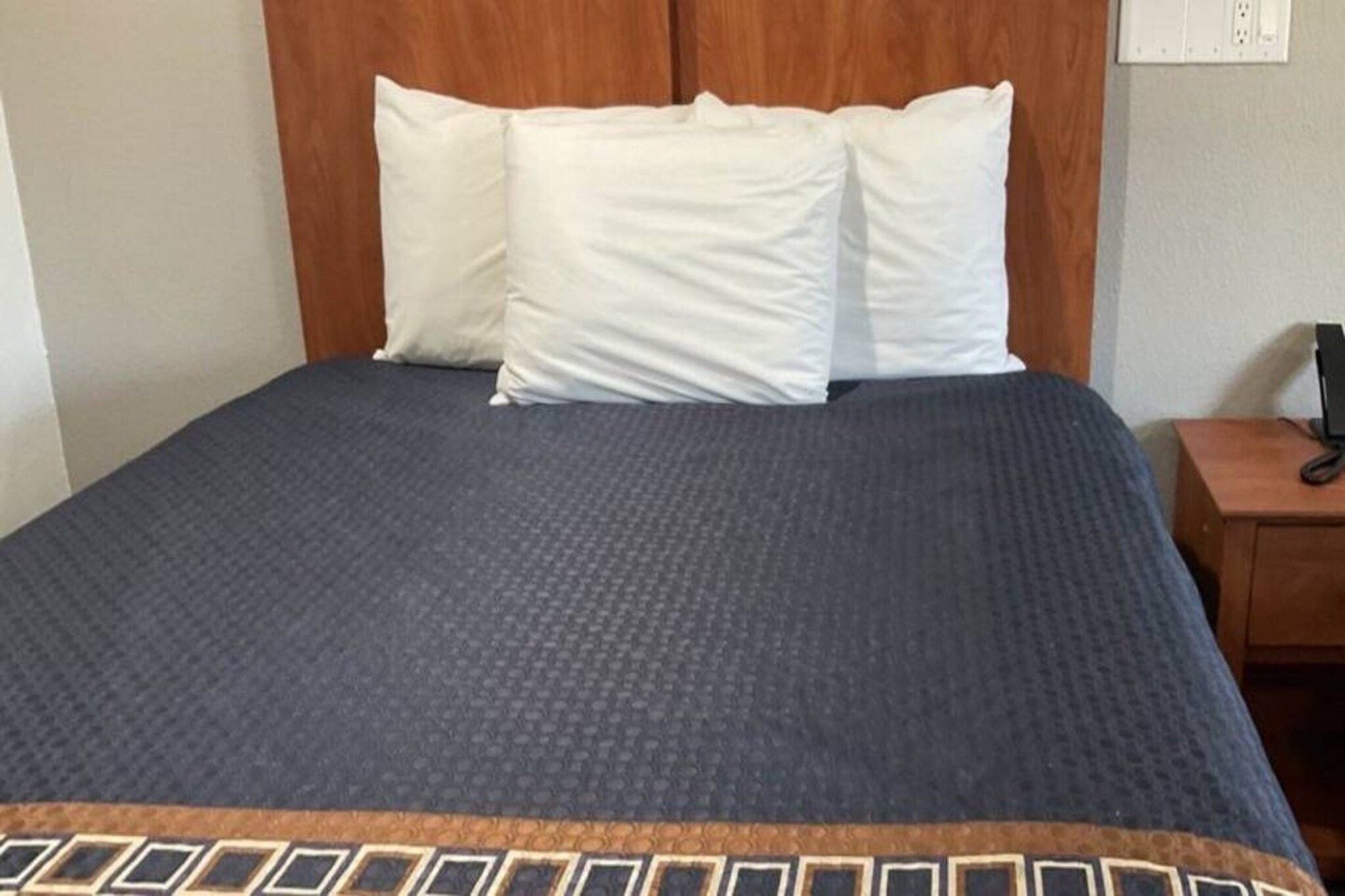 Ein Bett mit einer dunkelblauen Decke und einem Kissen mit geometrischem Muster.