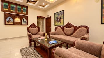 A room with a ceiling fan, a painting, a door, and a sofa set.