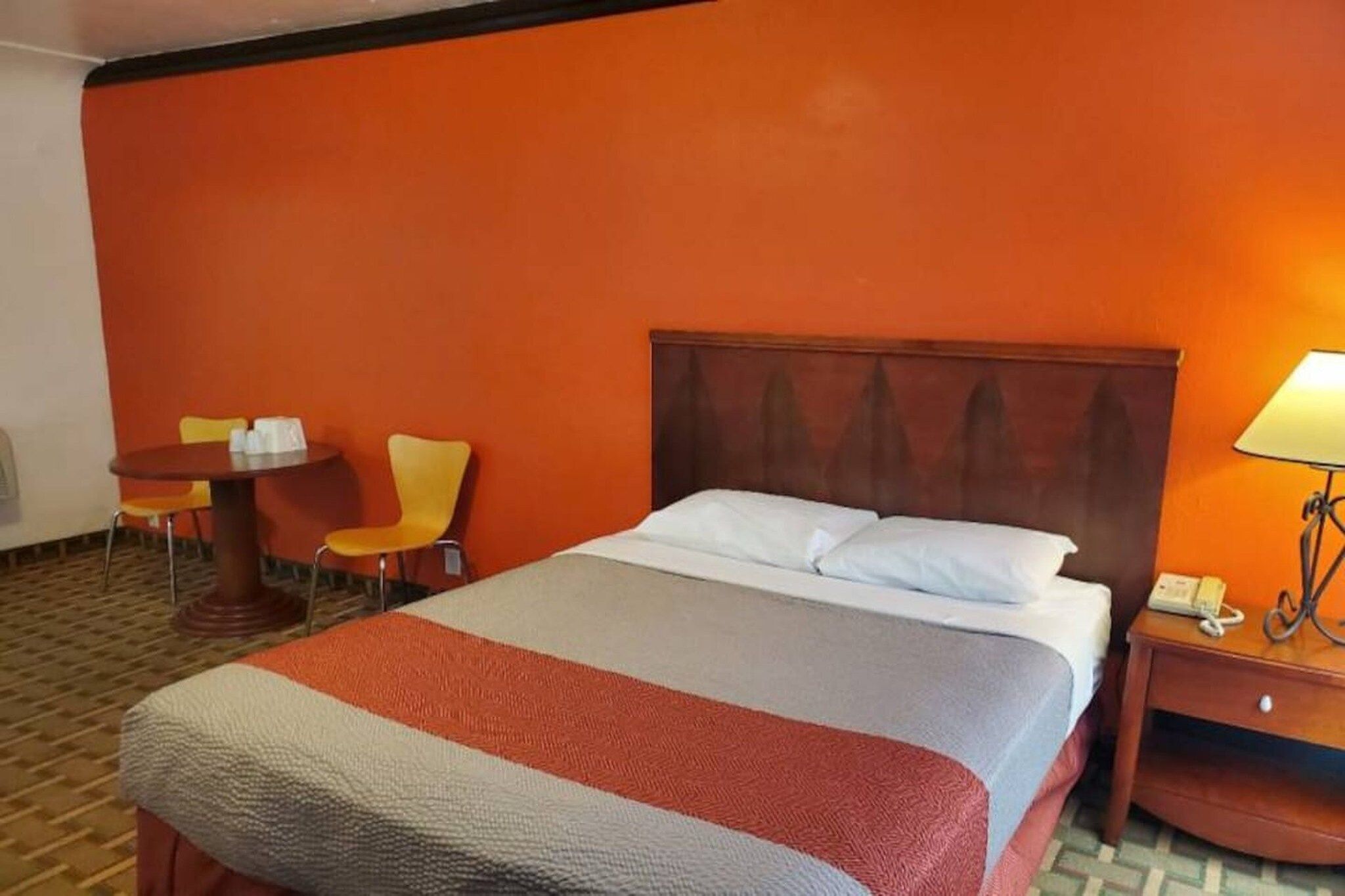 Une chambre d’hôtel avec un lit, une table de chevet, une chaise et une table.