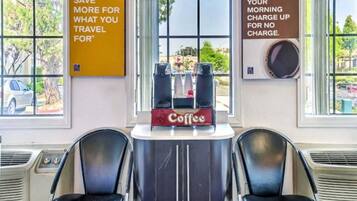 A room with two black chairs, a coffee station, and motivational posters on the walls.