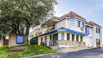 A hotel with a prominent '6' sign, a welcoming entrance, and a well-maintained lawn.