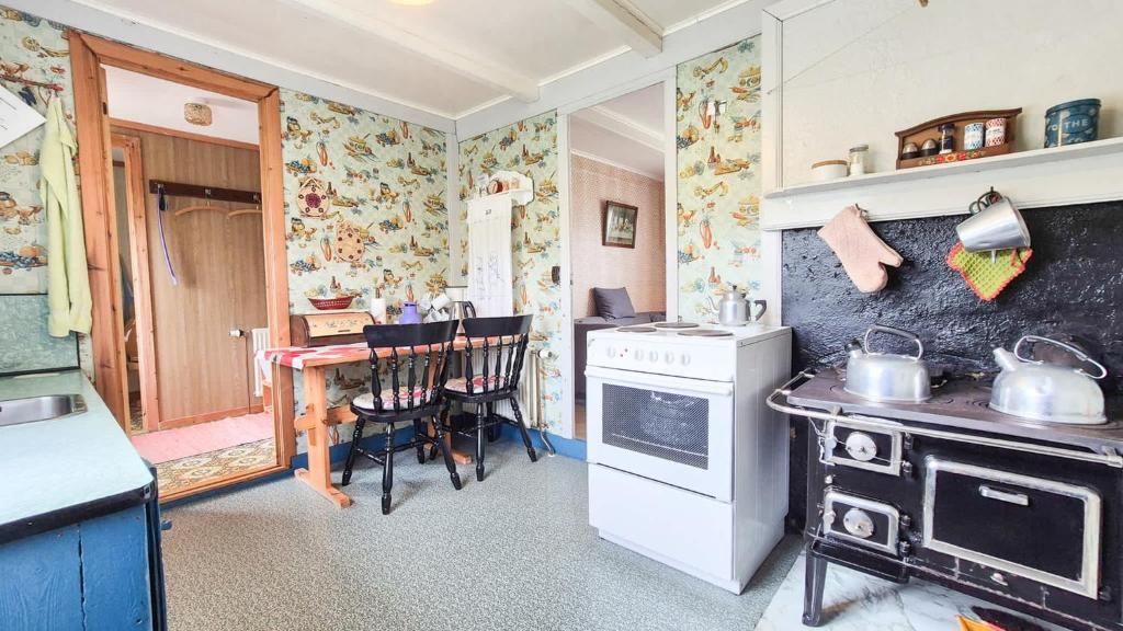 Una cocina compacta con una mesa de comedor, sillas, estufa y refrigerador.