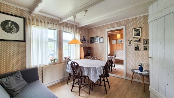 A dining area with a table and chairs, a sofa, and a radiator.