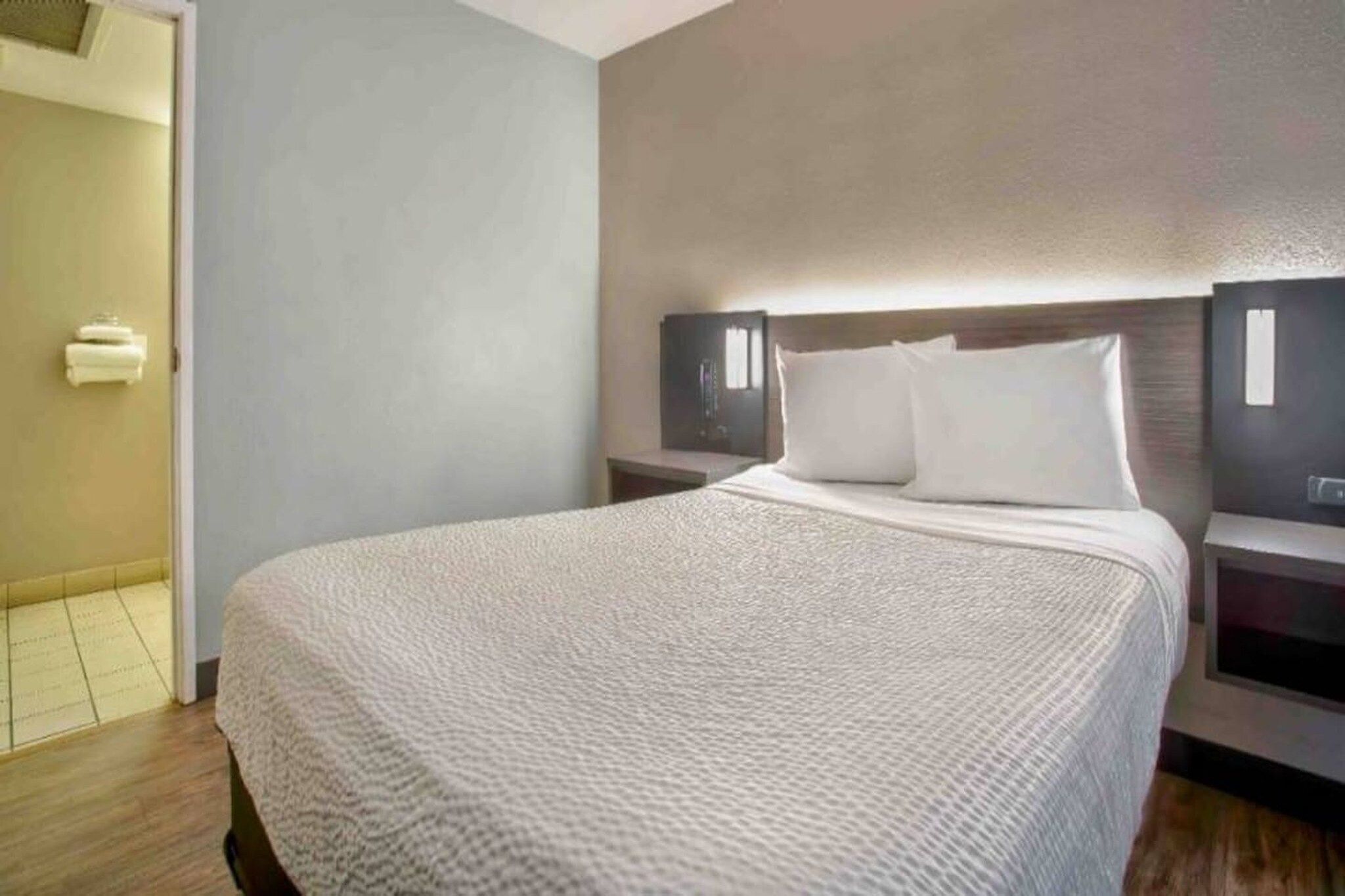 Een hotelkamer met een groot bed, twee nachtkastjes en een tv aan de muur.