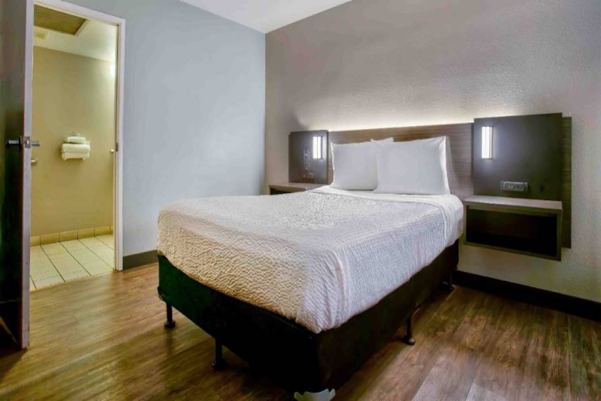 A hotel room with a bed, bedside tables, and a nightstand.