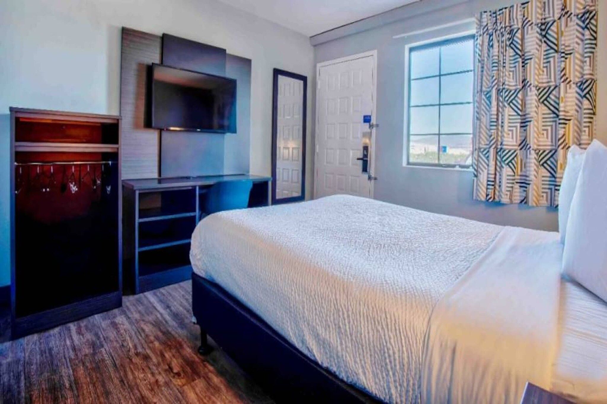 Une chambre d’hôtel équipée d’un lit, d’un bureau, d’une télévision et d’une armoire.