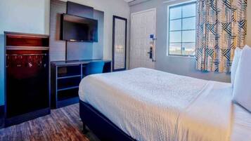 Une chambre d’hôtel équipée d’un lit, d’un bureau, d’une télévision et d’une armoire.