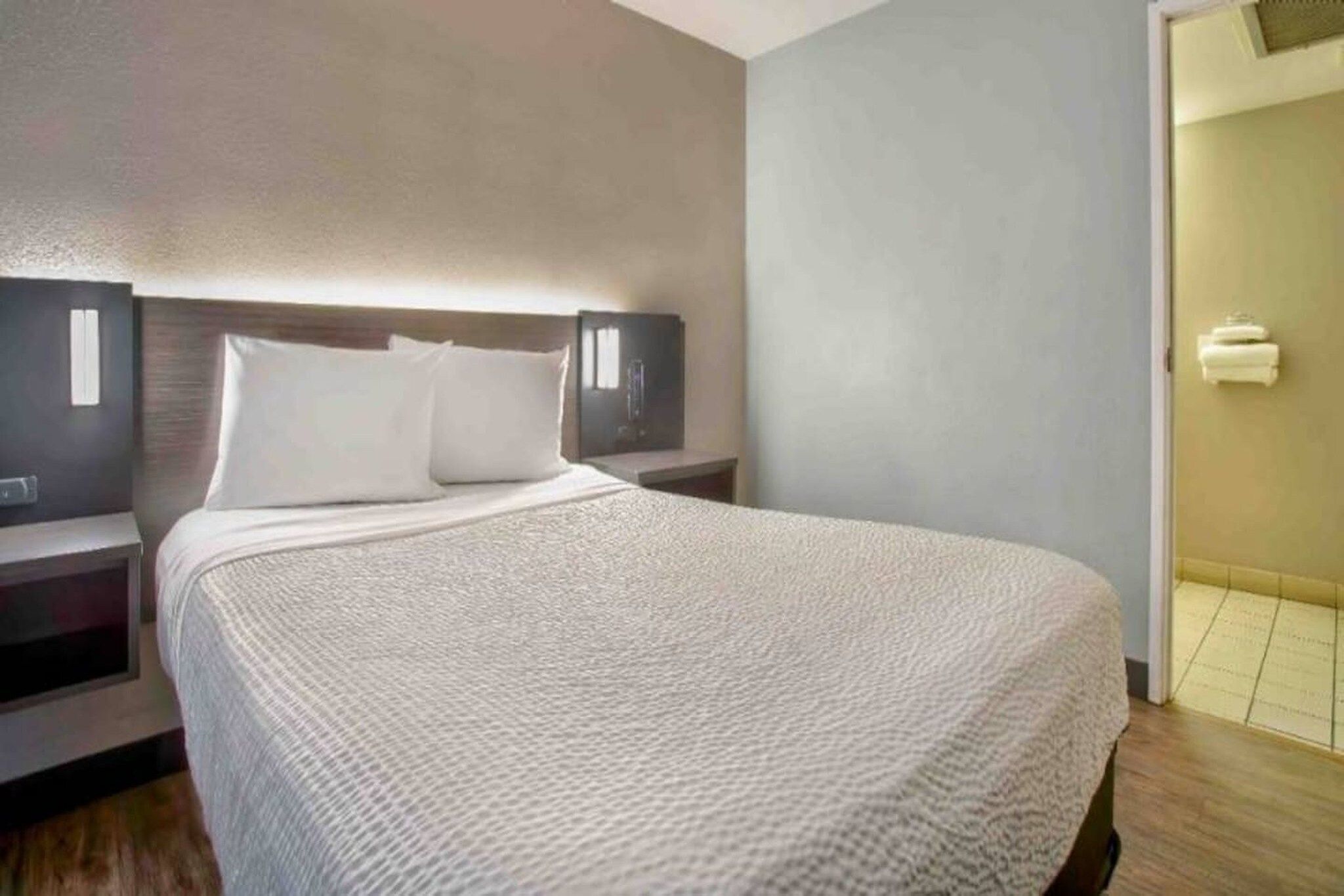 A hotel room with a large bed, two bedside tables, and a wall-mounted TV.