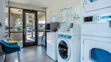 Una lavandería con lavadora, secadora y una silla.