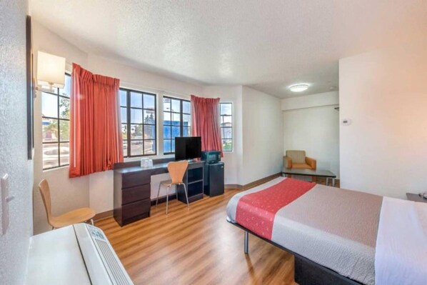 A hotel room with a bed, desk, chair, and a television. - Spacious 1 Queen Bed | ADA/Tub (Fairfield)